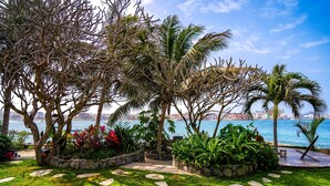 Ein angelegter Garten mit Palmen, einem Kiesweg und Blick auf das Wasser.