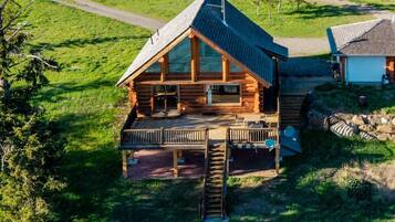 Une cabane en rondins avec un porche, un escalier et un petit bâtiment attenant.