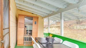Een overdekte buitenruimte met een tafel, stoelen en een barbecue.