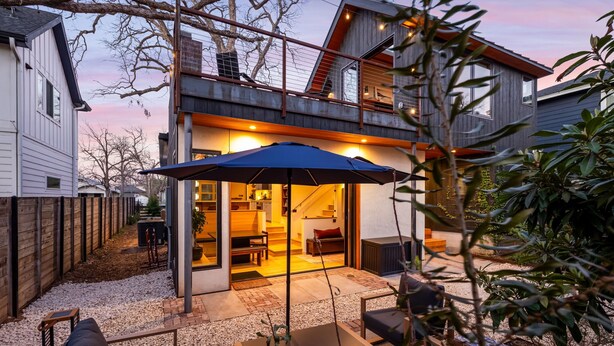 Uma casa moderna com varanda coberta, área de estar externa e escada que leva a um andar superior.