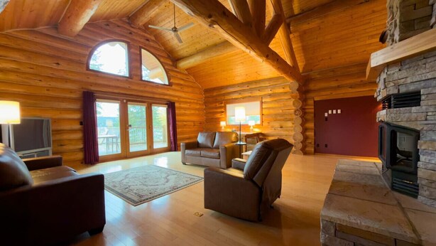A log cabin interior with a fireplace, wooden floors, and a cozy seating area.