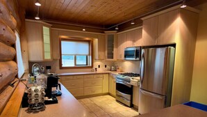 A modern kitchen with wooden cabinets, stainless steel appliances, and a large window.