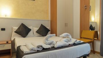 A hotel room with a bed, a nightstand, a wooden wardrobe, a mirror, and a chair.