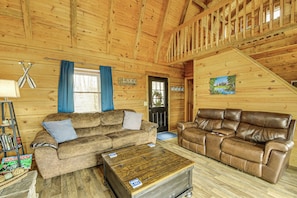 A wooden interior with two sofas, a coffee table, and a ladder with books.