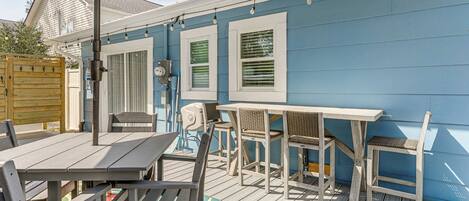 Eine Terrasse im Freien mit Tisch und Stühlen, ein Holzdeck und eine blaue Hauswand.