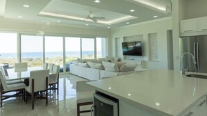 A modern kitchen with a large island, white cabinetry, and a built-in oven. - Ocean View Luxury + Sunset Terrace | Gated Resort (Del Coco Beach)