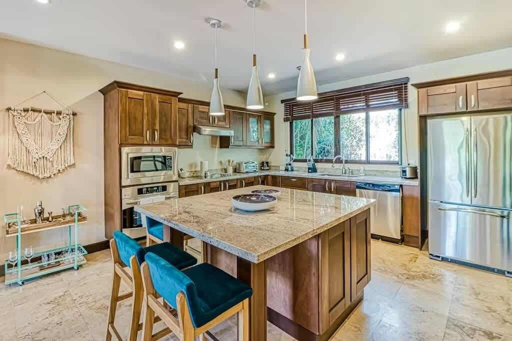 A modern kitchen with wooden cabinets, a central island, and stainless steel appliances.