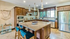 A modern kitchen with wooden cabinets, a central island, and stainless steel appliances. - Modern Condo + Pool Access | Gated Community (Coco)
