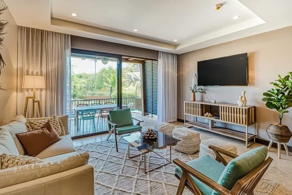 Ein modernes Wohnzimmer mit einer Couch, Sesseln, einem Couchtisch und einem Fernseher.