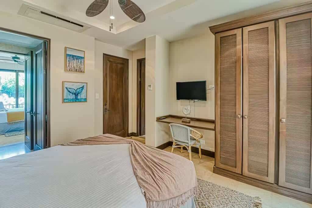 Um quarto com cama, escrivaninha, cadeira, televisão e guarda-roupa.