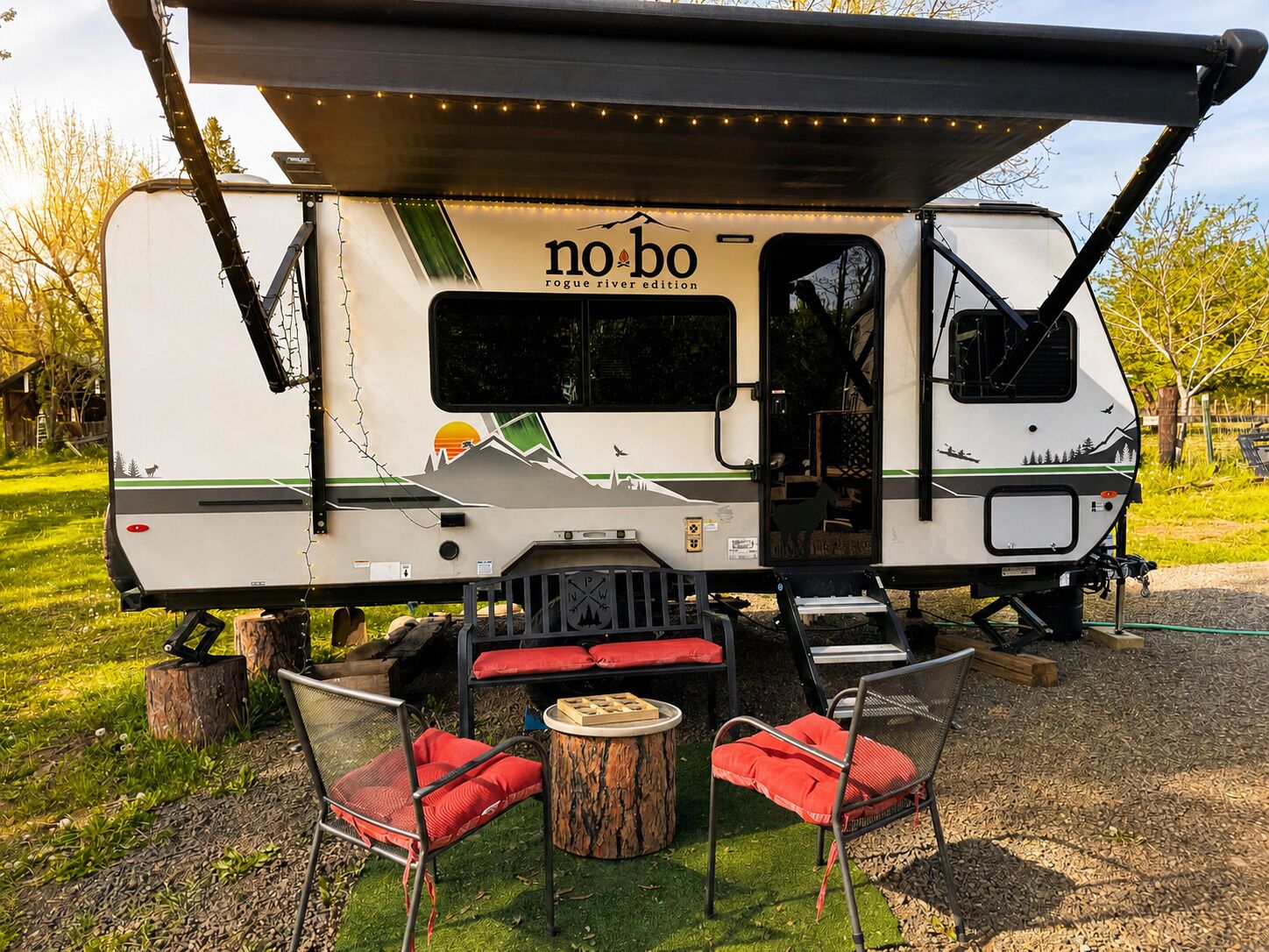 A no-bo RV with a covered dining area, a small table, and two chairs.