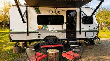 A no-bo RV with a covered dining area, a small table, and two chairs.