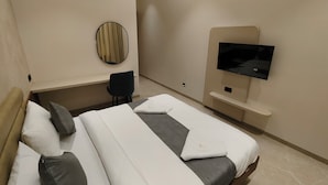 Une chambre d’hôtel avec deux lits, une télévision, un miroir et une chaise.