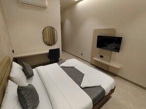 A hotel room with two beds, a TV, a mirror, and a chair.