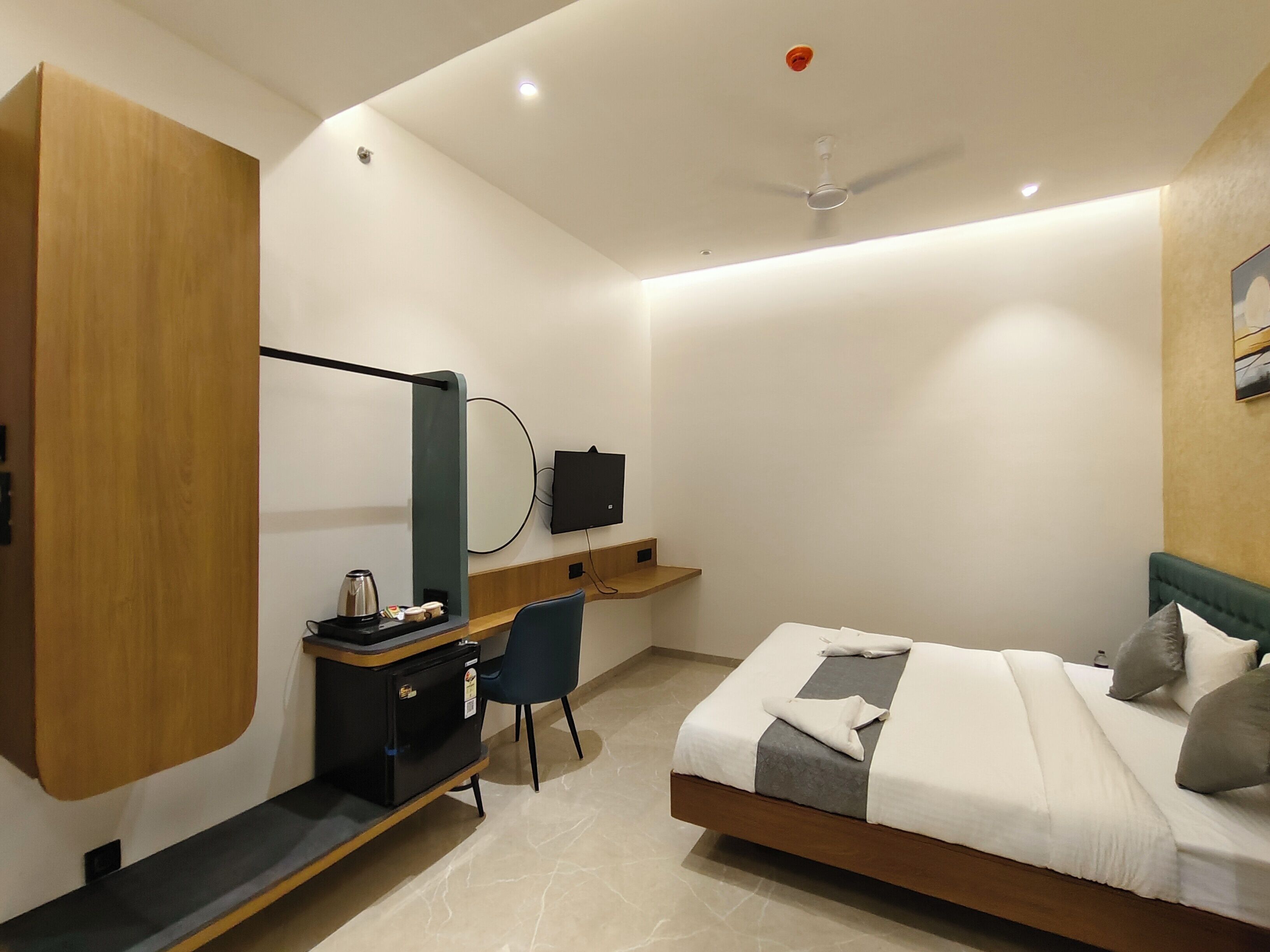 A modern hotel room with a bed, desk, chair, and a TV mounted on the wall.