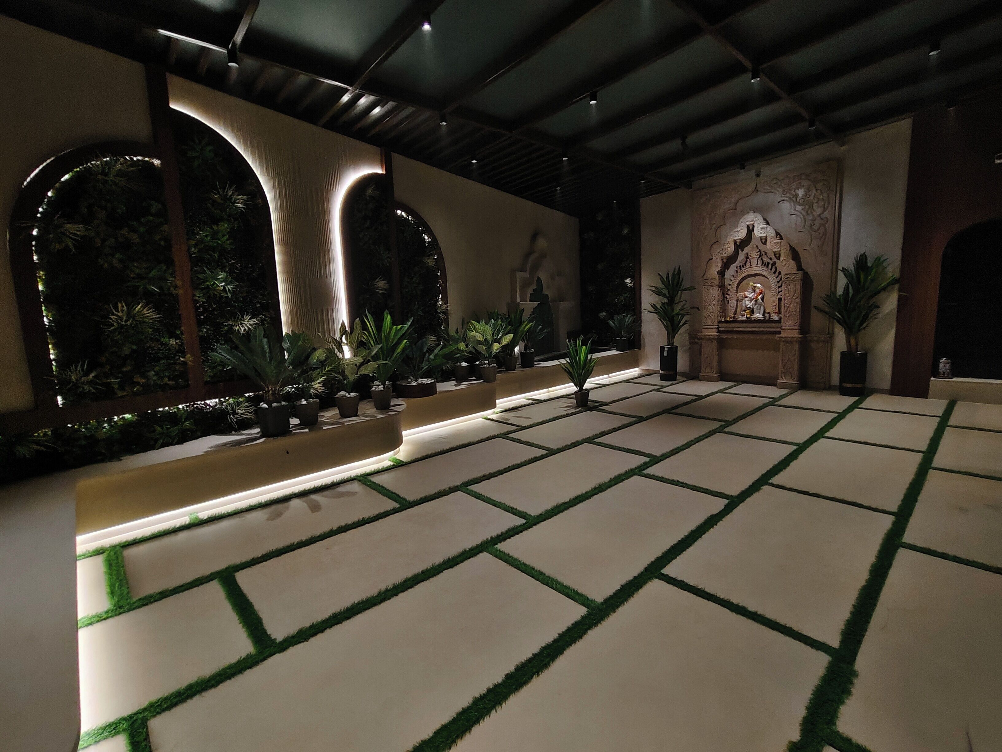 A spacious indoor area with a tiled floor, potted plants, and a decorative alcove with a statue.