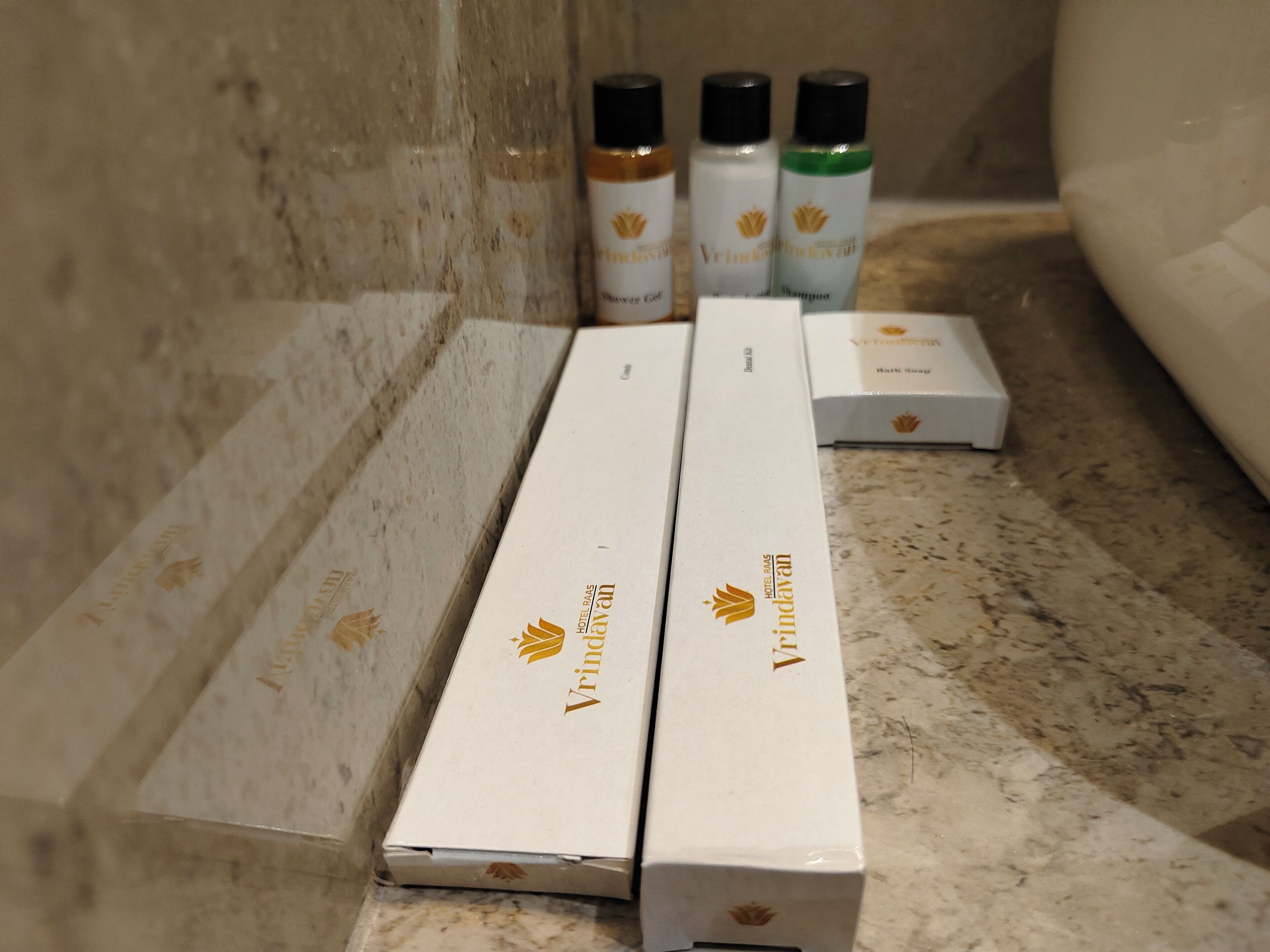 Three white boxes with a logo and text on a marble surface, likely containing hotel amenities.