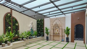 Une cour intérieure abritée, agrémentée d’un mur décoratif, d’une statue et de plantes en pot.