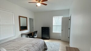 Une chambre à coucher comprenant un lit, un bureau, une armoire et un ventilateur de plafond.