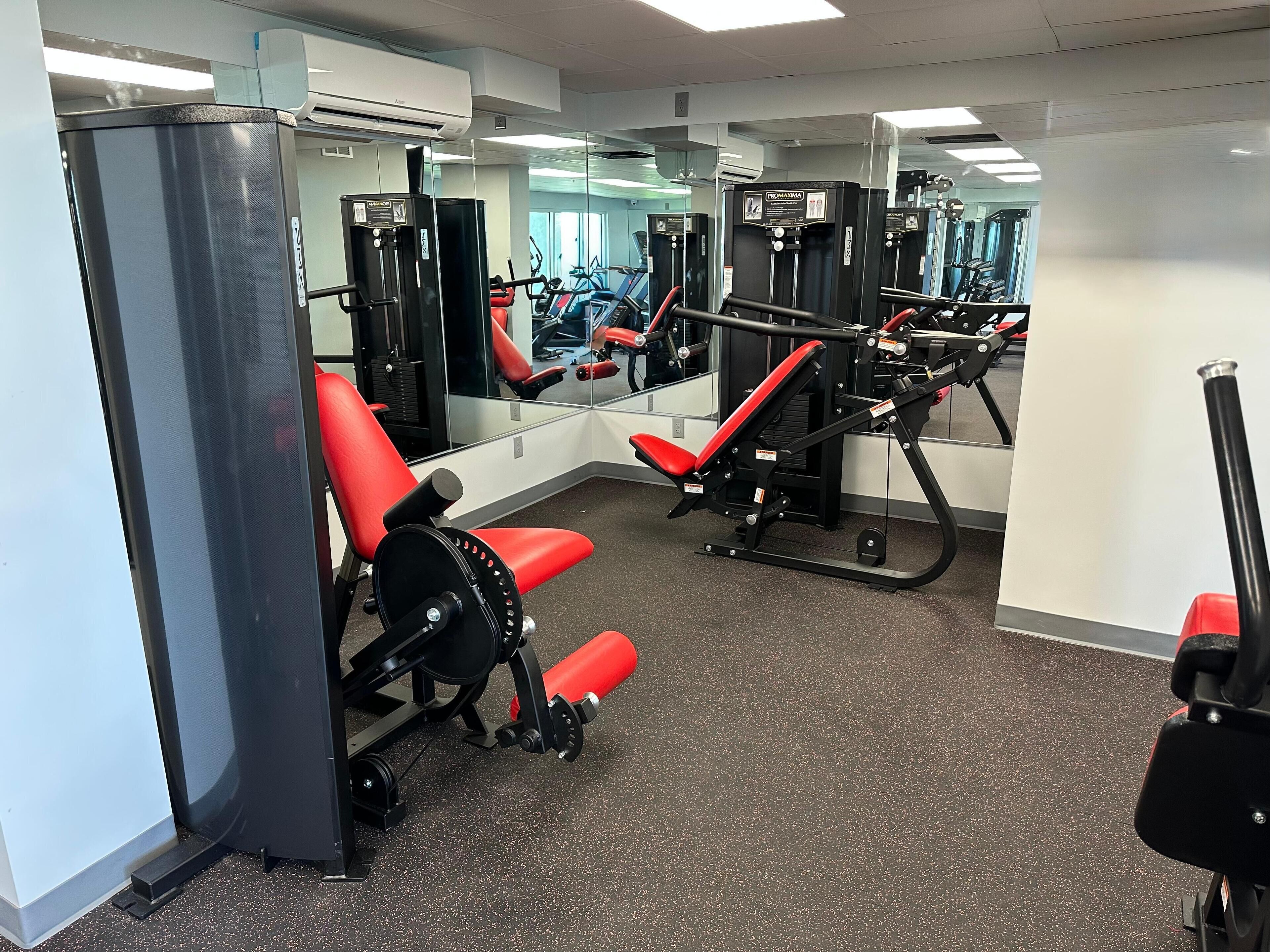 A gym with various exercise machines, including a red bench and a weight stack.