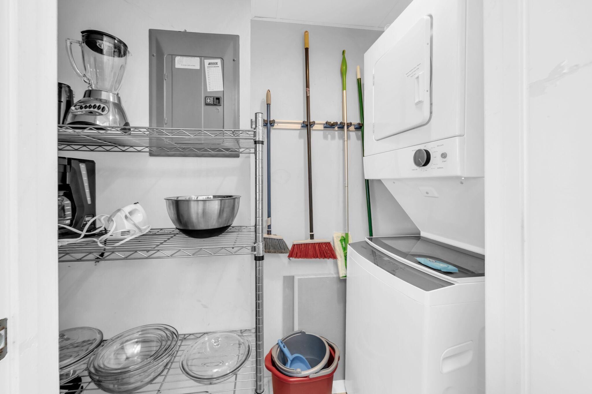 A compact kitchen with a blender, a metal bowl, a mop, and a bucket.