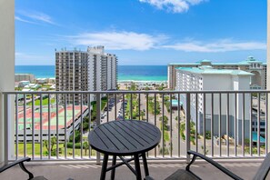 A balcony with a table and chairs, overlooking a beach and a parking lot. - Ariel Dunes I 1306 (Miramar Beach)