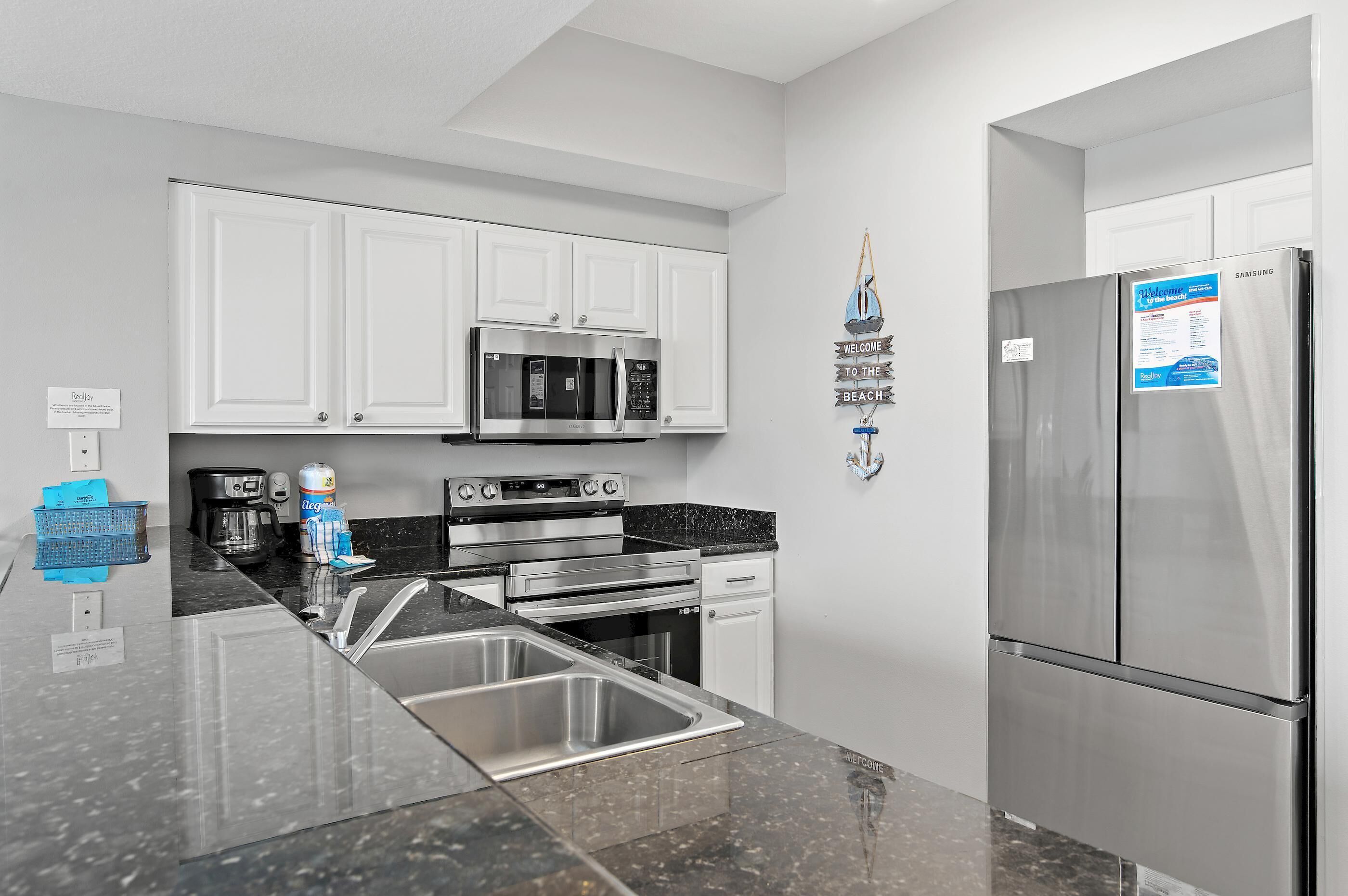 A modern kitchen with stainless steel appliances, white cabinets, and a granite countertop.
