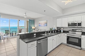 A modern kitchen with white cabinets, a black countertop, and stainless steel appliances. - Ariel Dunes I 1306 (Miramar Beach)