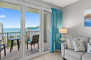 A balcony with a view of the sea, a chair, a table, and a sofa with pillows. - Ariel Dunes I 1306 (Miramar Beach)