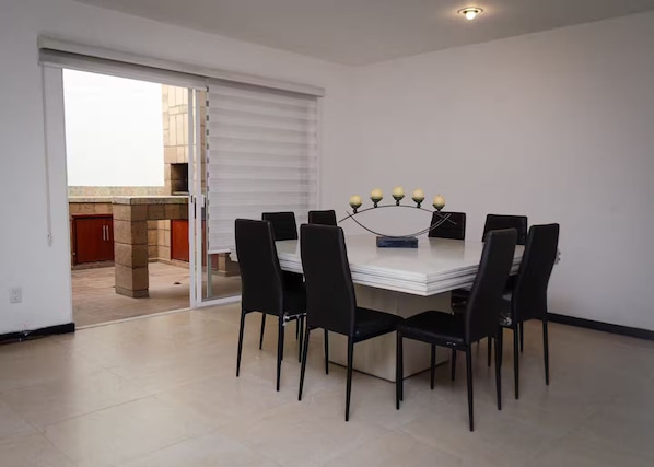 A dining area with a white table, black chairs, and a chandelier.