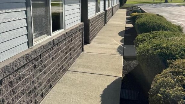 A building with a covered walkway, windows, and a brick base. - The Melrose Motel  (Sandusky)