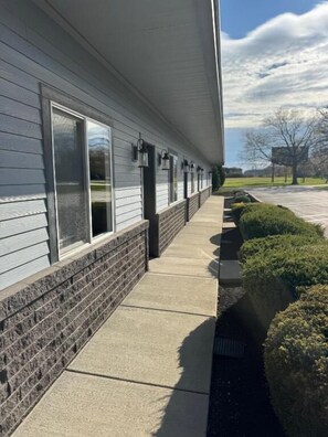 A building with a covered walkway, windows, and a brick base.