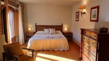 A bedroom with a large bed, wooden headboard, two bedside tables with lamps, a wooden dresser, and a chair.