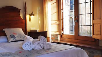 A hotel room with a bed, a nightstand, a lamp, and a window with a view of the outside.