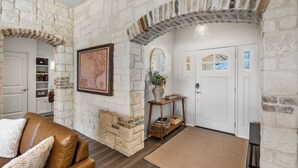 A room with stone walls, a wooden bench, a white door, and a brown rug.