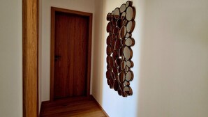 Een hal met een houten deur en een spiegelbeeld kunstwerk aan de muur.