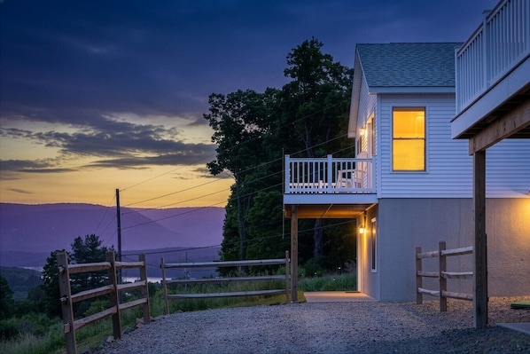 A house with a balcony, a gravel driveway, and a view of the mountains.