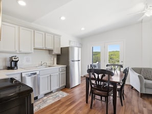 A kitchen with white cabinets, a refrigerator, a coffee maker, and a dining area with a table and chairs.