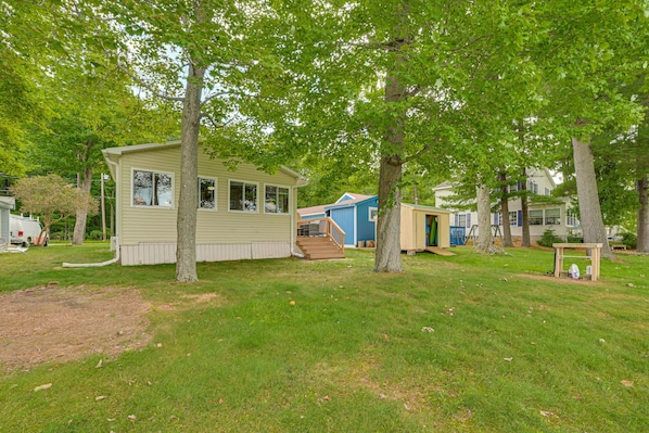 A row of mobile homes with a grassy yard and trees.