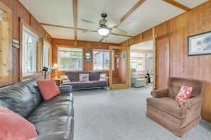 A cozy living room with a leather couch, a brown armchair, and a ceiling fan.