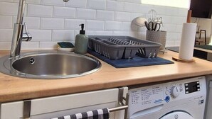 A compact kitchen with a sink, a washing machine, and a wicker light fixture. - Right in the center at the foot of the cathedral (Beauvais)