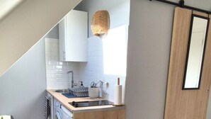 A compact kitchen with a washing machine, a dining table with chairs, and a large mirror. - Right in the center at the foot of the cathedral (Beauvais)