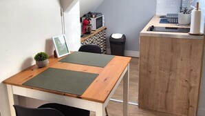 A compact kitchen with a wooden table and black chair, a small potted plant, and a microwave on the counter. - Right in the center at the foot of the cathedral (Beauvais)