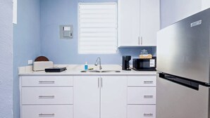 A compact kitchen with white cabinets, a stainless steel refrigerator, a coffee maker, and a window with blinds. - Spacious San Juan Home /Parking/ Near Plaza  Las  Americas (San Juan)