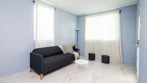 A room with a dark sofa, a round white table, and two black speakers. - Spacious San Juan Home /Parking/ Near Plaza  Las  Americas (San Juan)