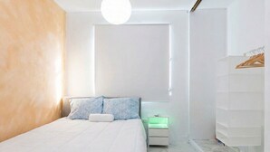 A modern bedroom with a bed, bedside tables, a hanging light fixture, and a wardrobe. - Spacious San Juan Home /Parking/ Near Plaza  Las  Americas (San Juan)
