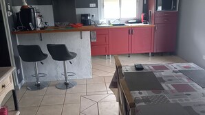 A compact kitchen with a central island, two bar stools, a microwave, and a red cabinet.