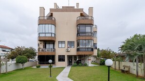 Un immeuble résidentiel moderne à plusieurs étages, doté de balcons, de grandes fenêtres et d’une pelouse bien entretenue.