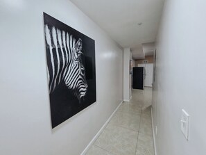 A hallway with a large zebra artwork on the wall, a tiled floor, and a door at the end. - Twinset / 2 King Beds / Elevator / 2 Ensuite / W/D (Philadelphia)