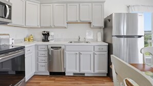 A modern kitchen with white cabinetry, stainless steel appliances, and a wooden floor. - Lakeview Retreat Near Finger Lakes! (Lawrenceville)